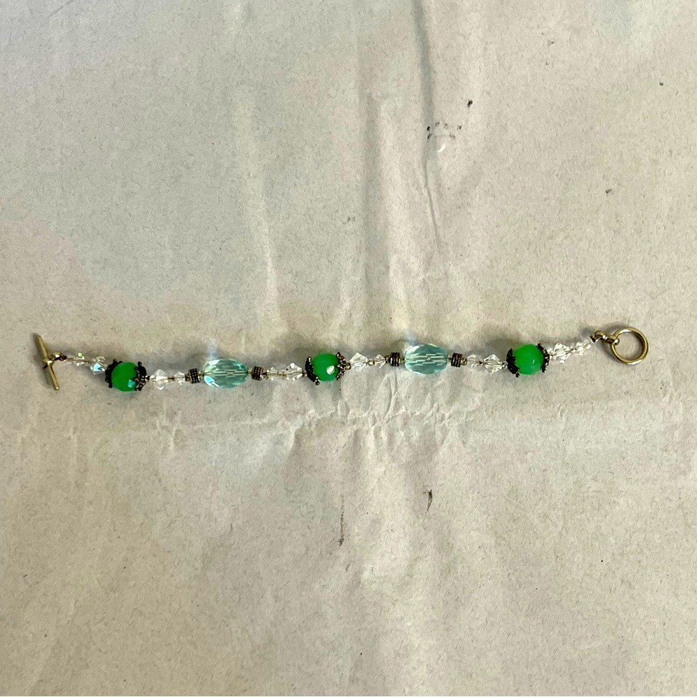 A green beaded bracelet with charms good condition
